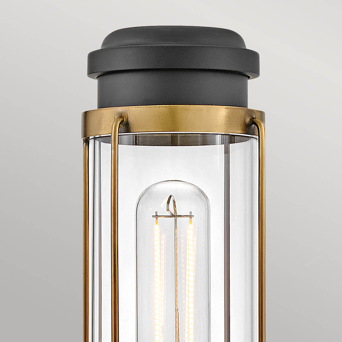 Détail du haut : capuchon noir, anneau en laiton et verre transparent autour de l'ampoule.