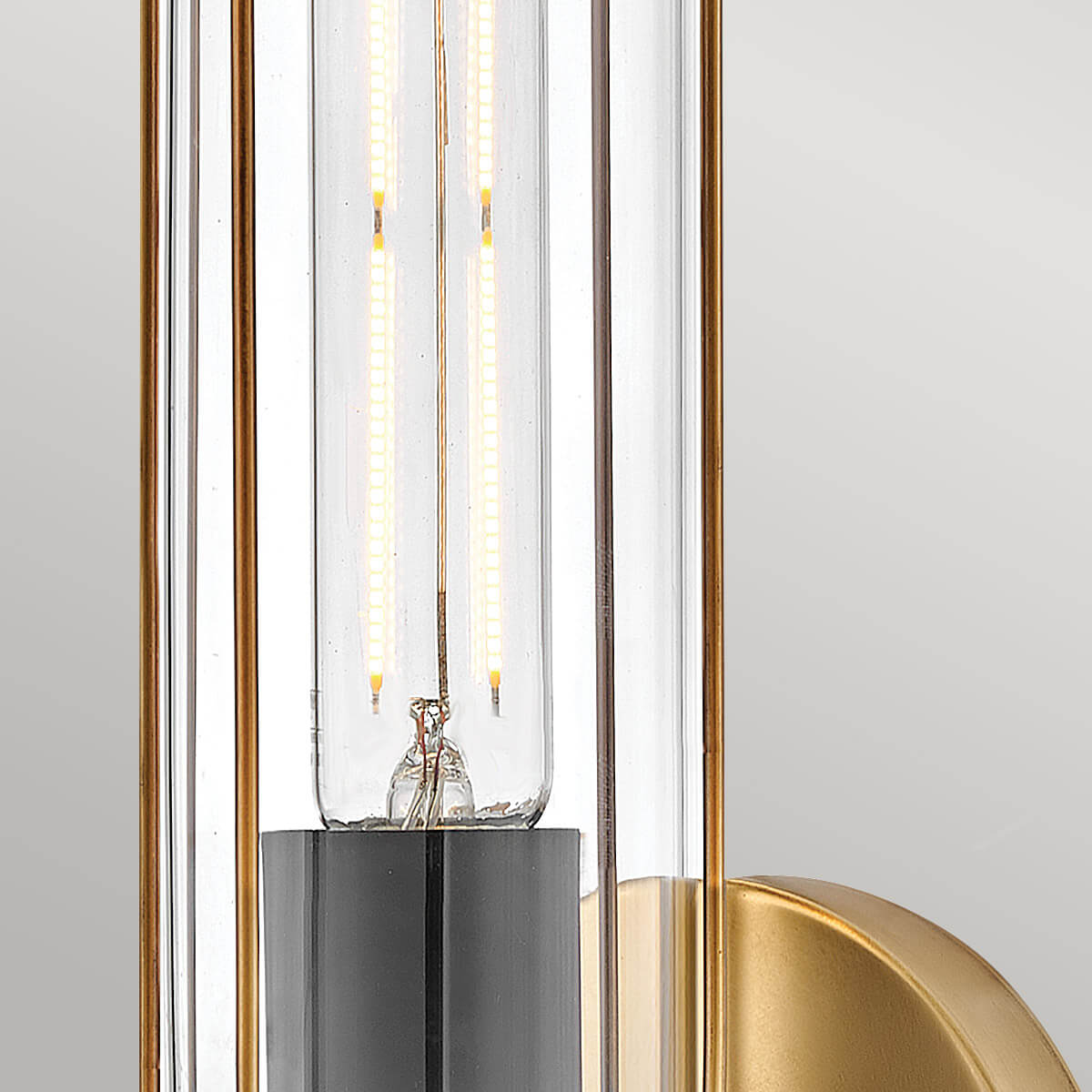 Gros plan sur l'ampoule à filament LED et les tiges en laiton dans le verre.