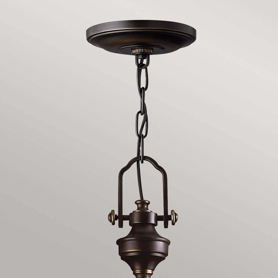 Gros plan sur la fixation au plafond, la chaîne et le sommet du luminaire en bronze.