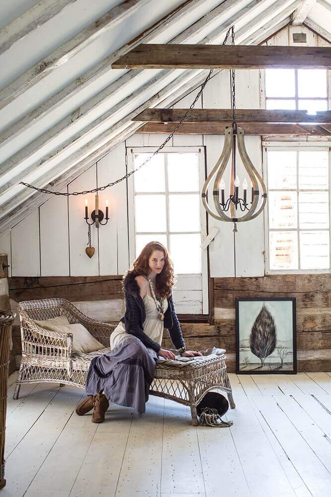 Mise en ambiance du lustre suspendu dans un grenier avec femme assise et lumière naturelle.