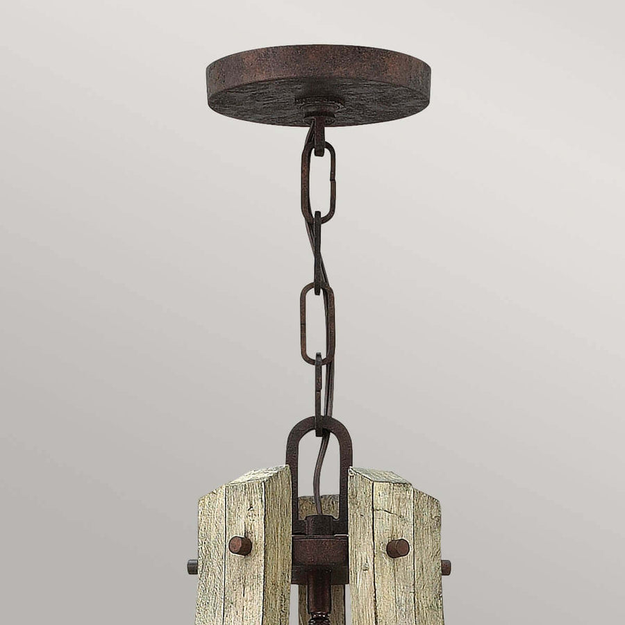Détail de la fixation au plafond, chaîne et boîtier en métal rouille et bois brut.