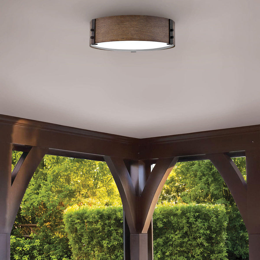 Luminaire fixé sous une véranda en bois avec vue sur le jardin