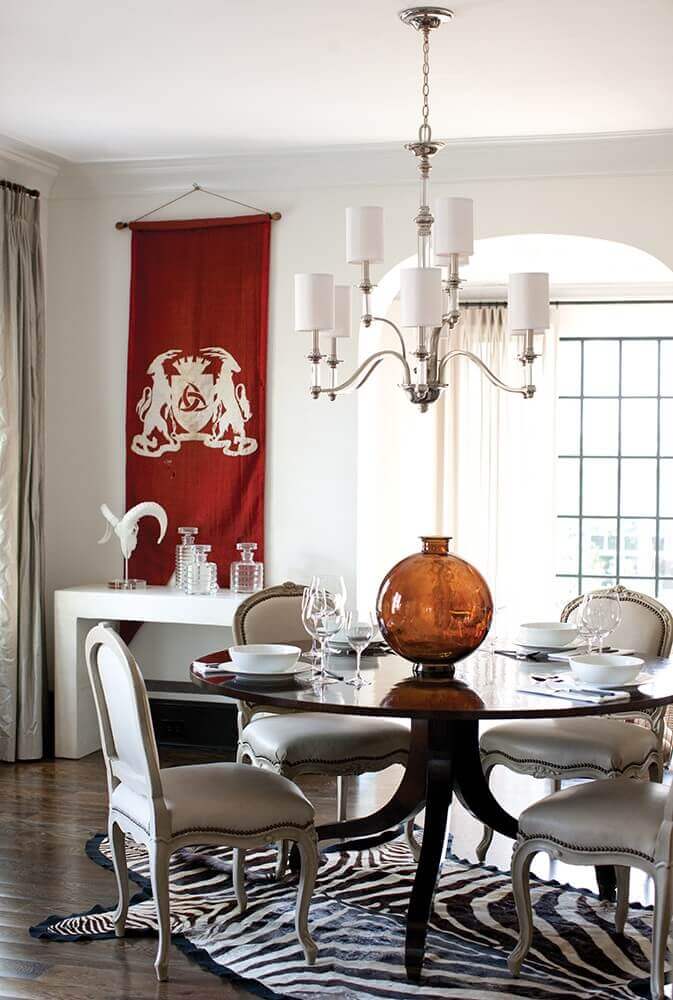 Lustre en situation au-dessus d'une table de salle à manger, avec tapis zébré et vase ambré.
