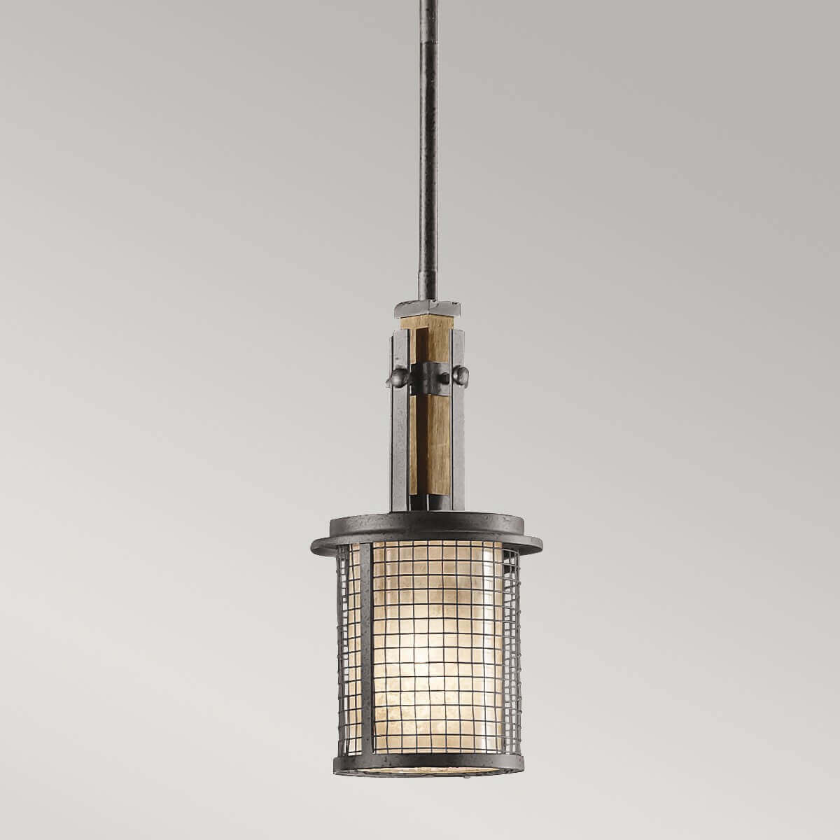 Gros plan sur la grille métallique et le détail de bois clair du luminaire suspendu.