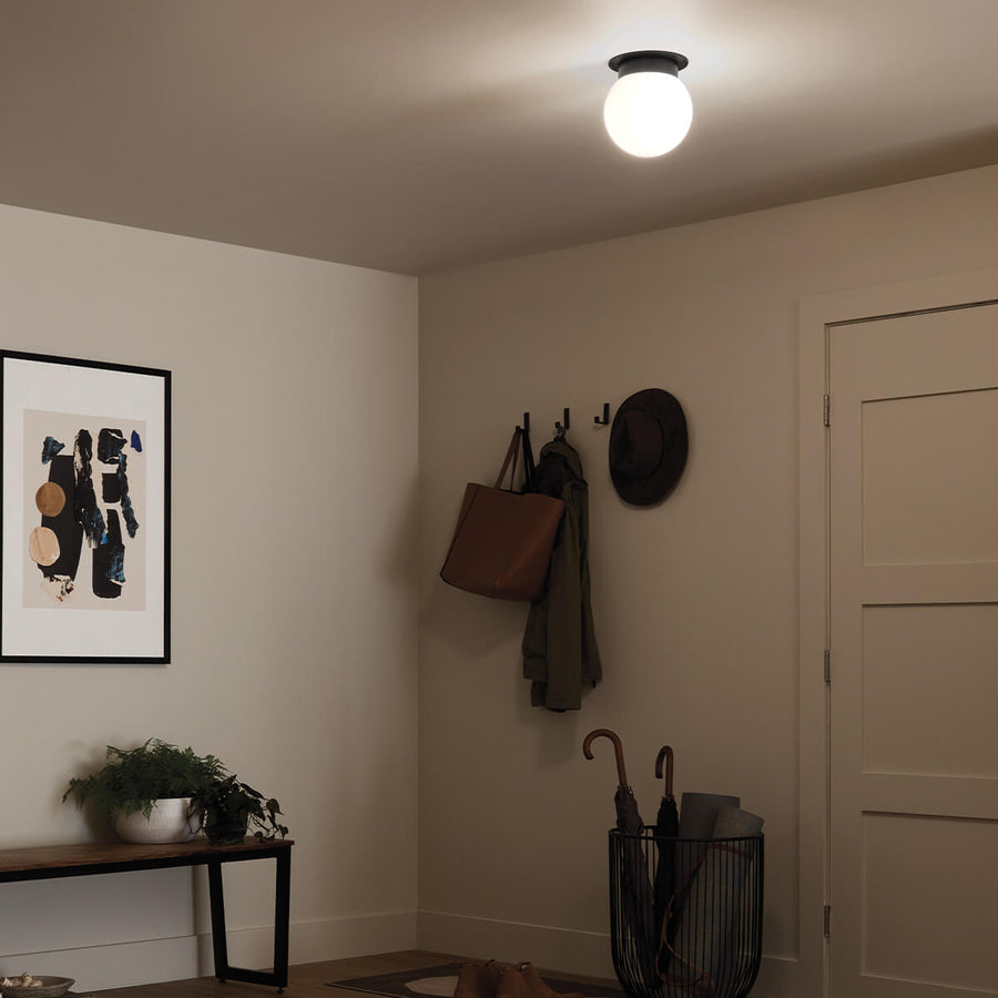 Vue en soirée de l'entrée éclairée par le plafonnier rond au plafond.