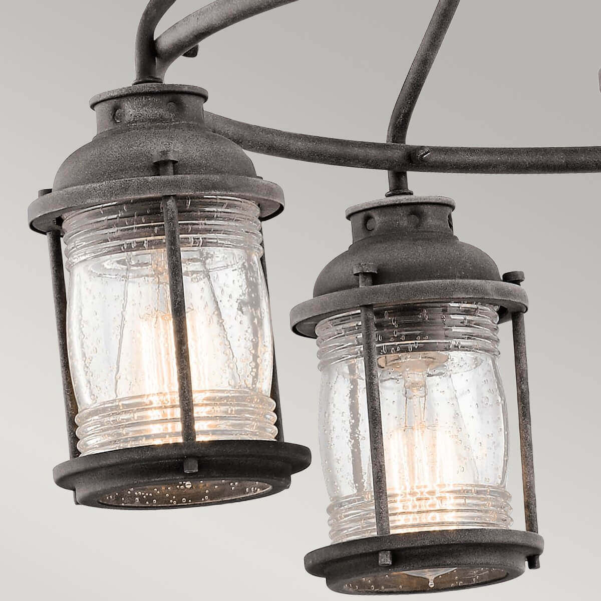 Gros plan sur deux lanternes en verre moucheté et leur ampoule allumée.