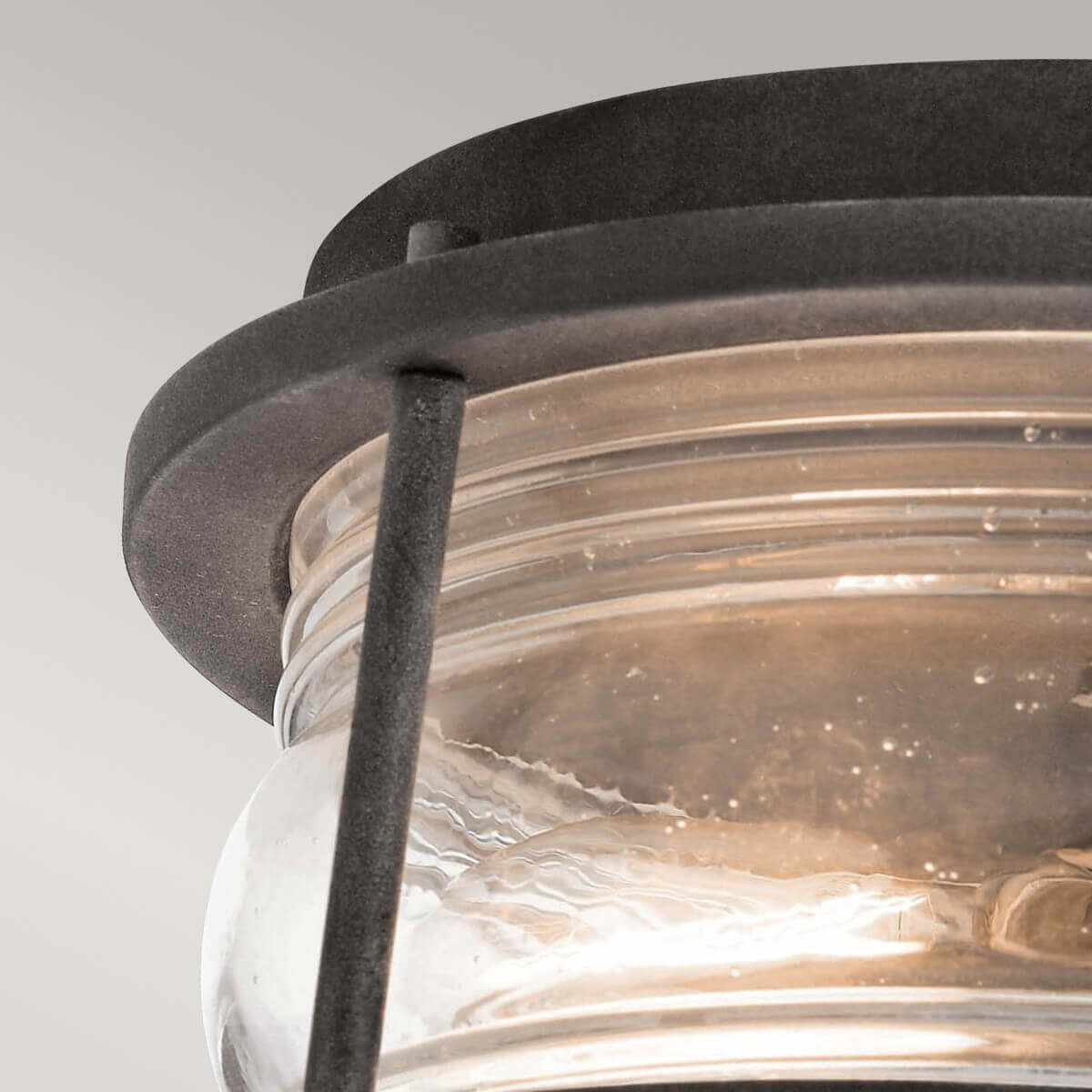 Détail du cerclage métallique supérieur et du verre texturé sous la lumière.