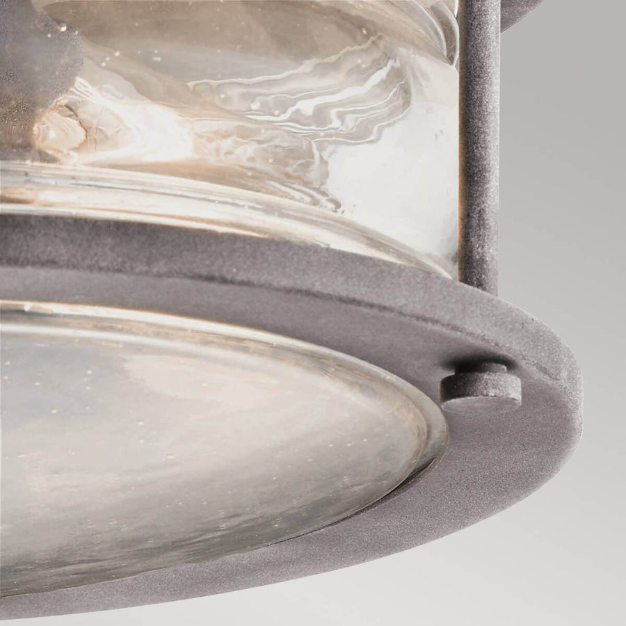 Gros plan sur la bague inférieure, le boulon et le verre bombé du plafonnier.