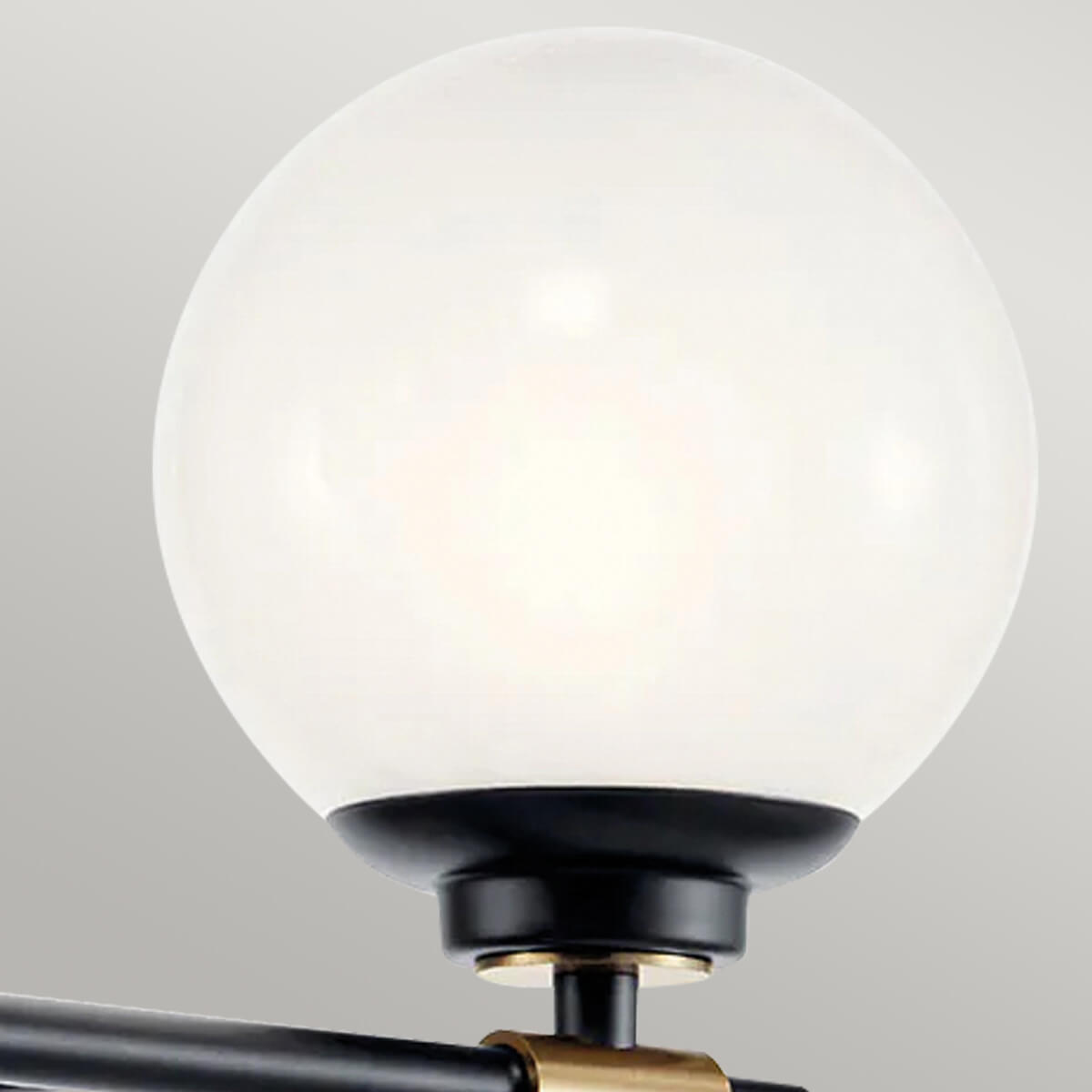 Gros plan sur un globe en verre opalin et sa bague en laiton sur support noir.