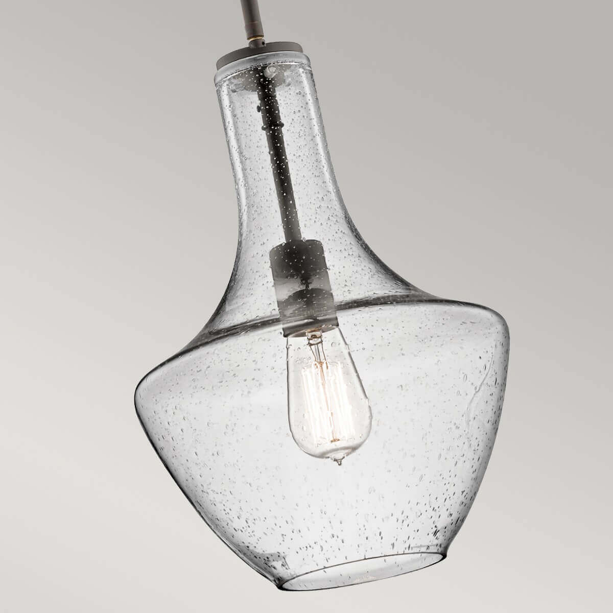 Gros plan sur l'abat-jour en verre bullé et l'ampoule Edison allumée