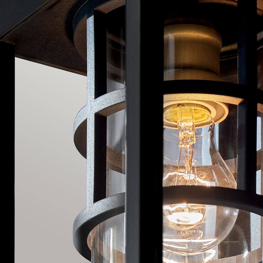 Gros plan sur l'ampoule dorée et la douille laiton sous le verre transparent