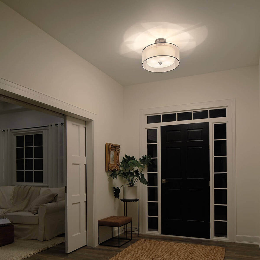 Vue en situation du luminaire éclairé au plafond d'un couloir avec mobilier et plante.