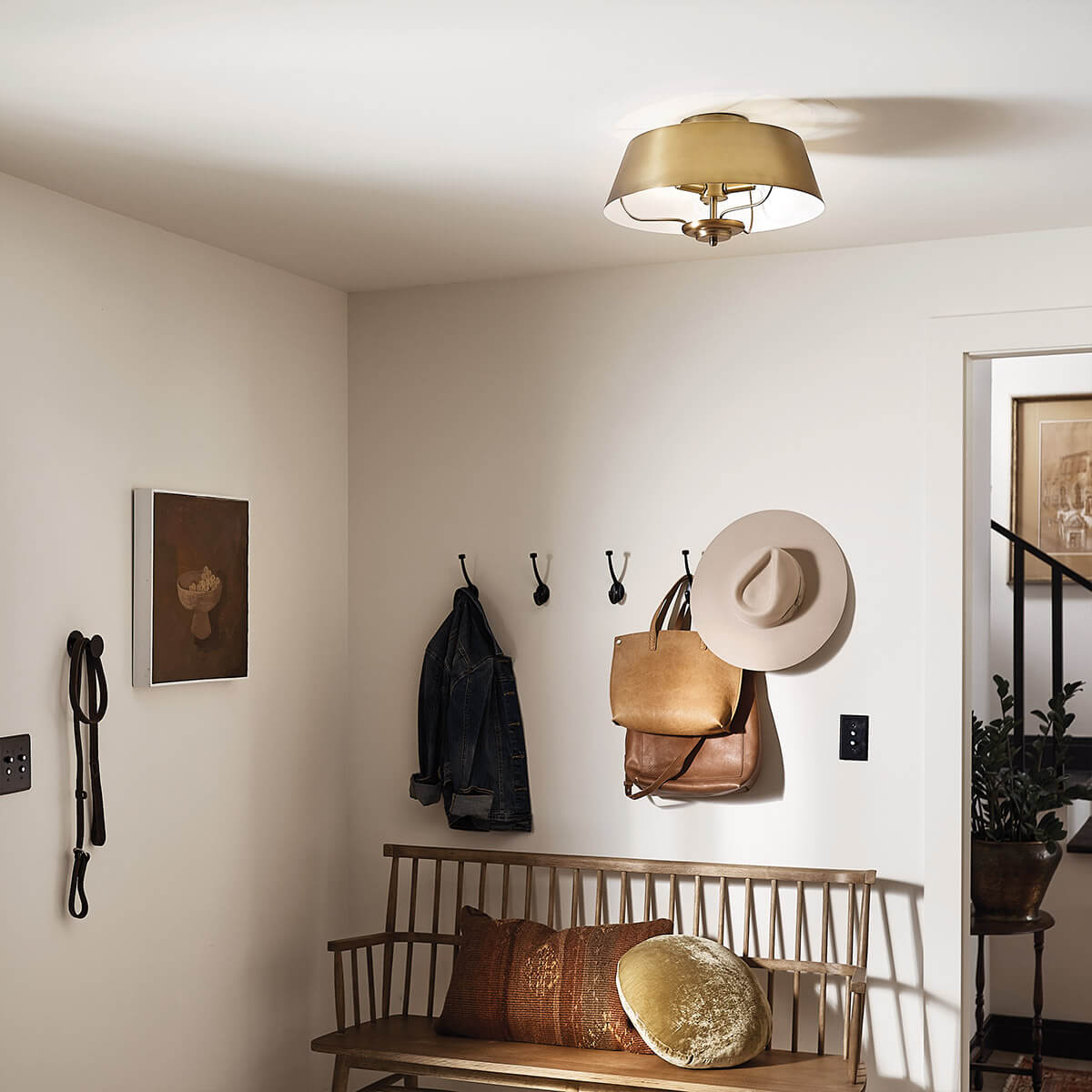 Mise en ambiance du luminaire installé au plafond d'une entrée avec banc