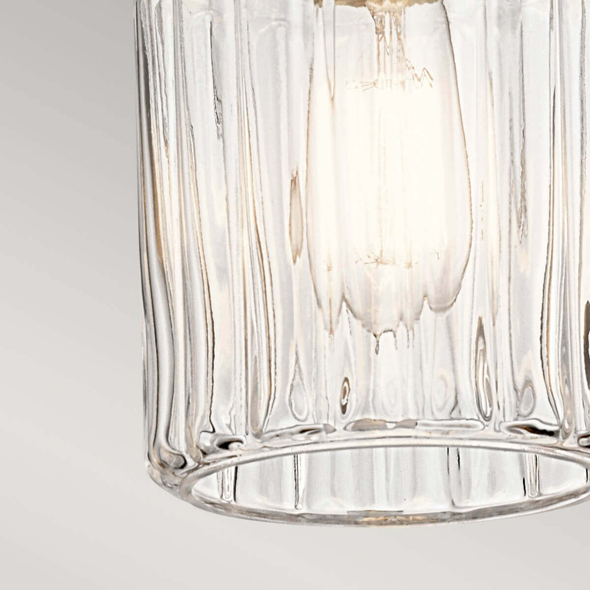 Détail du bas du verre cylindrique strié, ampoule allumée visible à l'intérieur.
