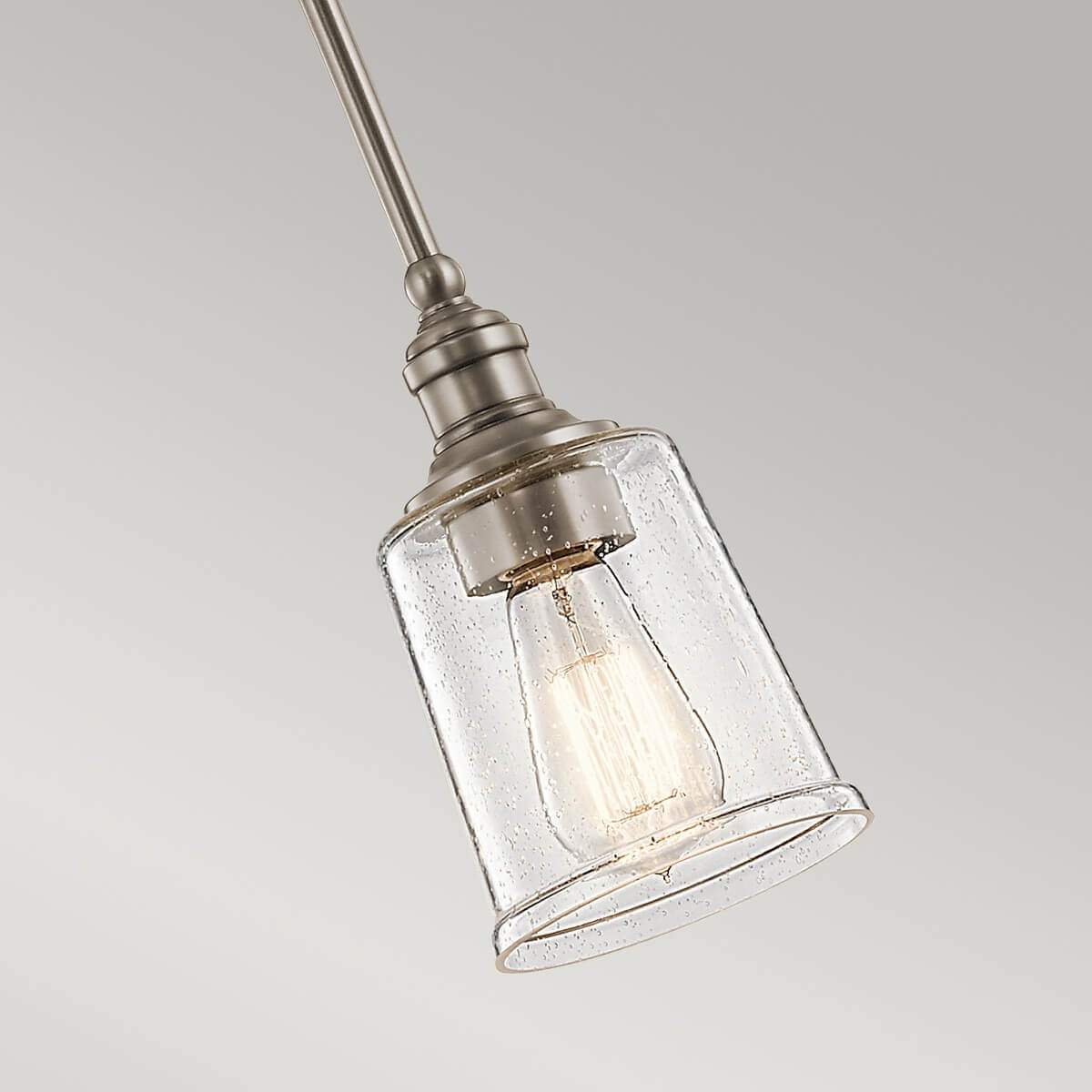 Gros plan sur l'abat-jour en verre grésé et l'ampoule Edison allumée