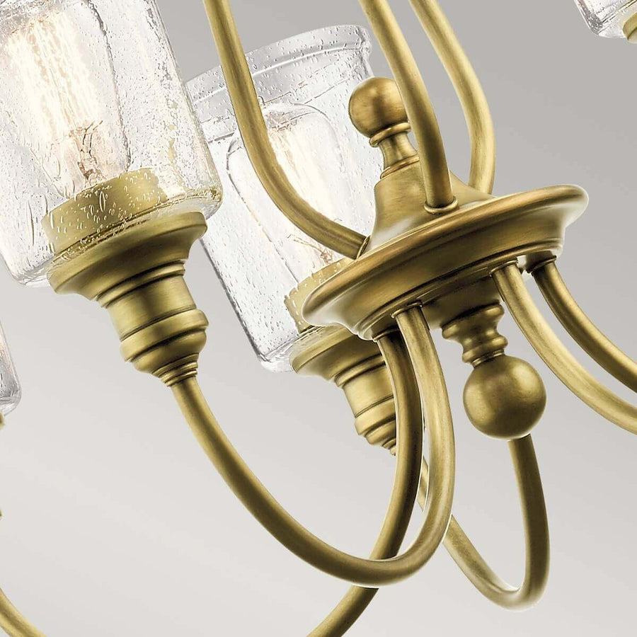 Détail du centre du luminaire : bras courbés en laiton et coupes en verre granité.