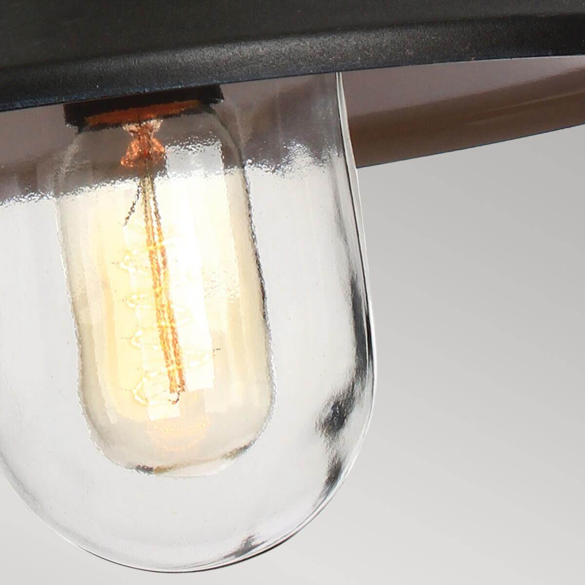 Détail de l'ampoule à filament doré sous le globe de verre transparent.