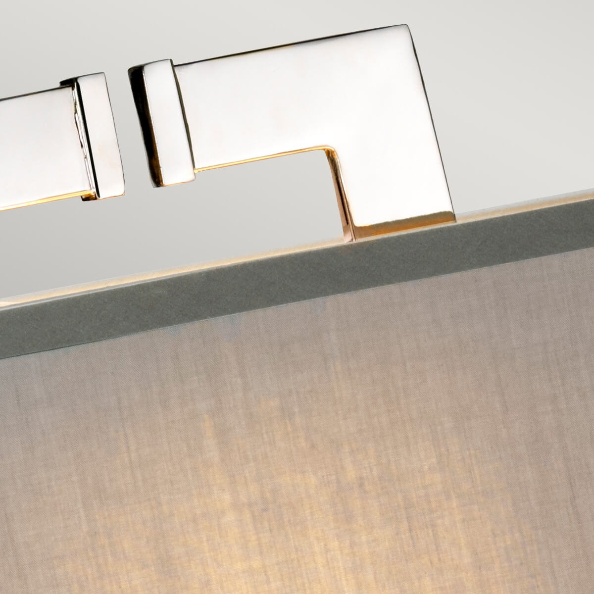 Détail du haut de la lampe montrant le support métallique nickelé et la finition polie.