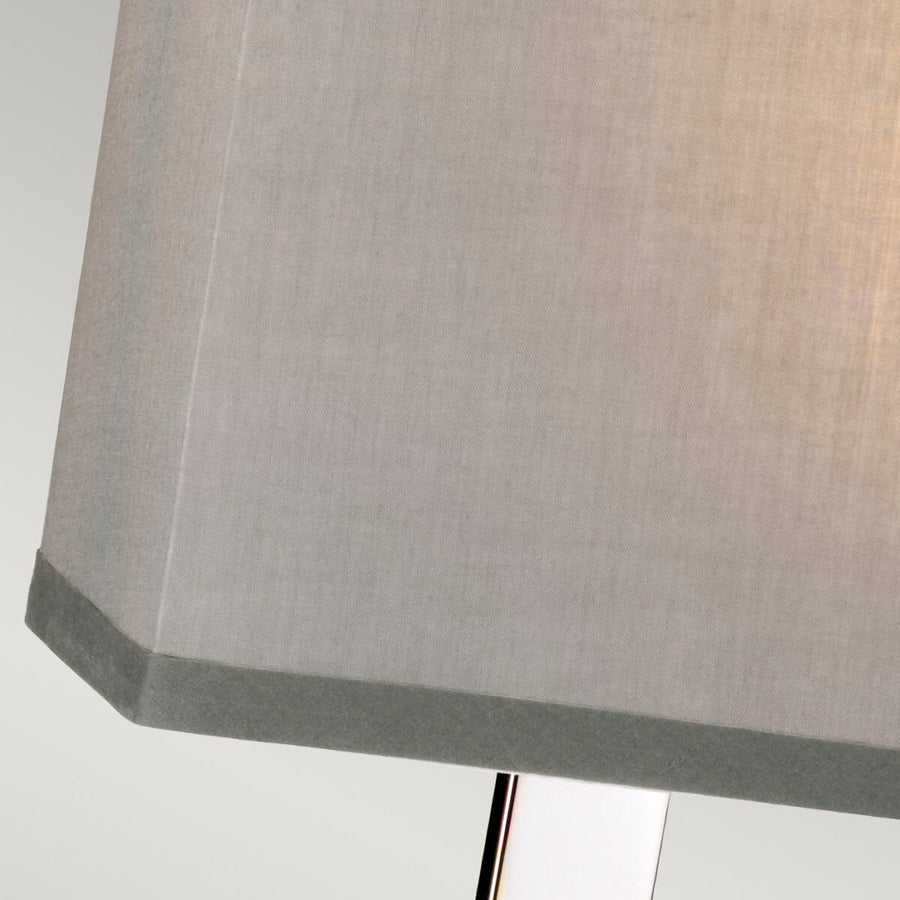 Gros plan sur un coin de l'abat-jour gris clair avec bordure noire et armature visible.
