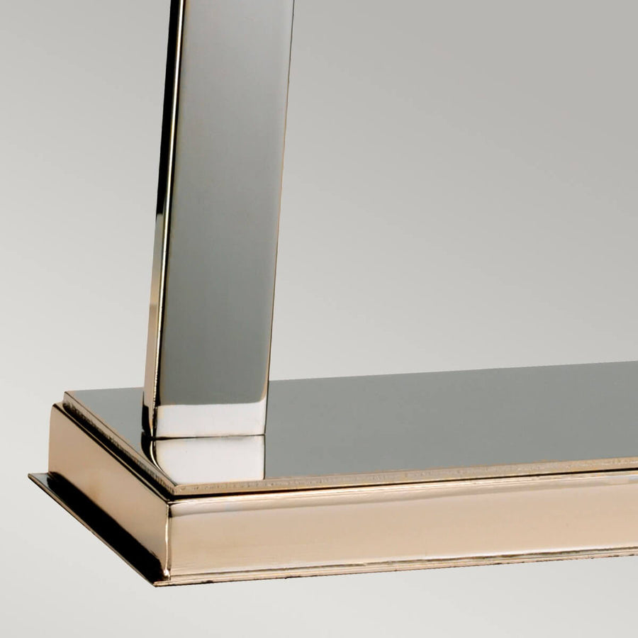 Détail de la base rectangulaire en métal nickelé poli avec montant vertical et reflets.