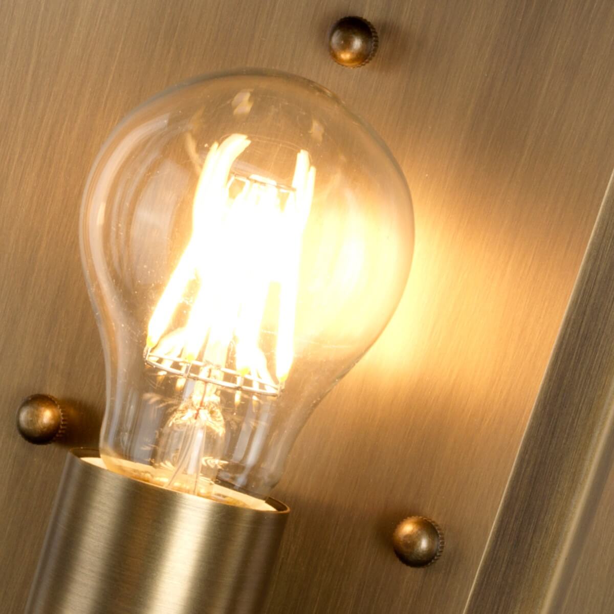 Détail rapproché de l'ampoule Edison allumée et de sa douille en laiton