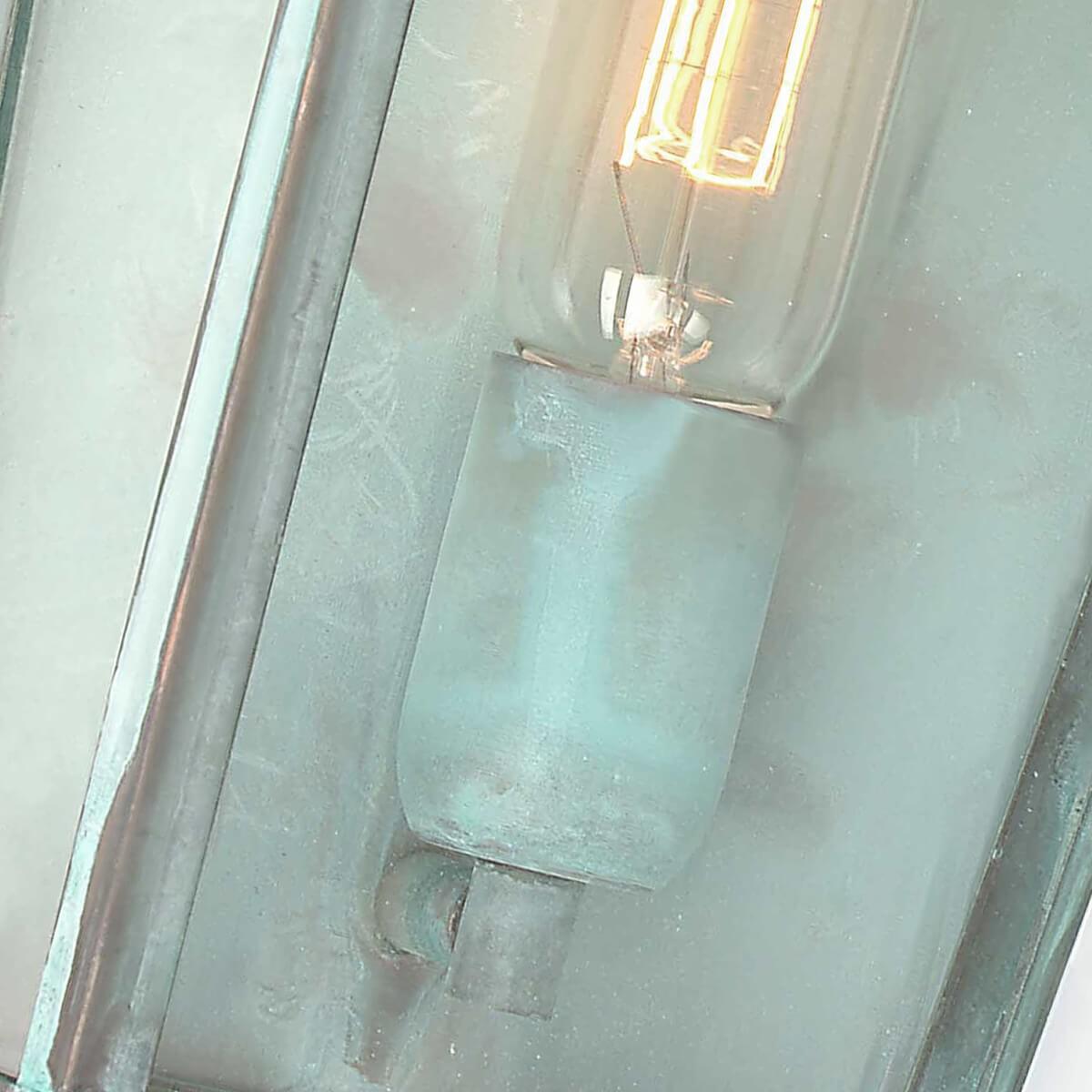 Gros plan sur la douille et l'ampoule allumée derrière la vitre du luminaire