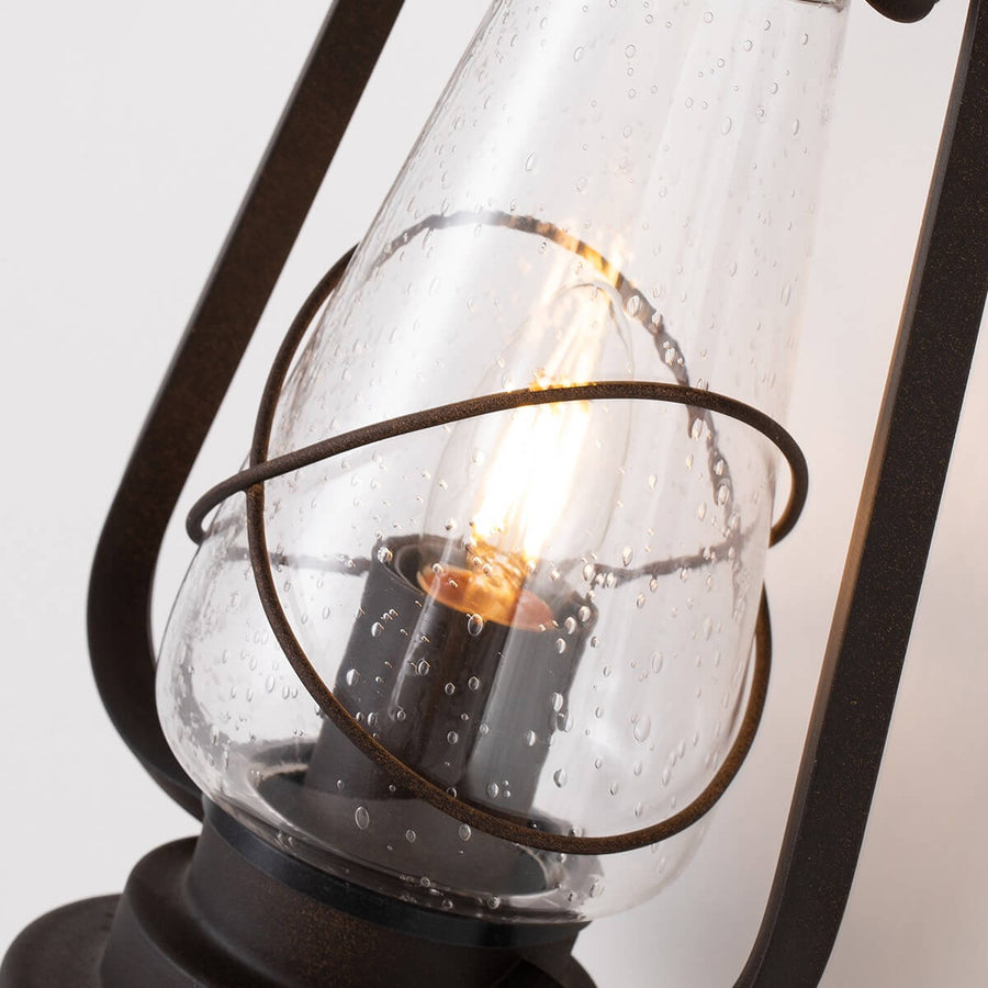 Gros plan sur le verre gouttelé, l'anneau métallique et l'ampoule à filament allumée.