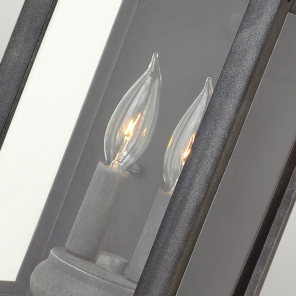 Détail de deux ampoules flammes allumées derrière le verre transparent