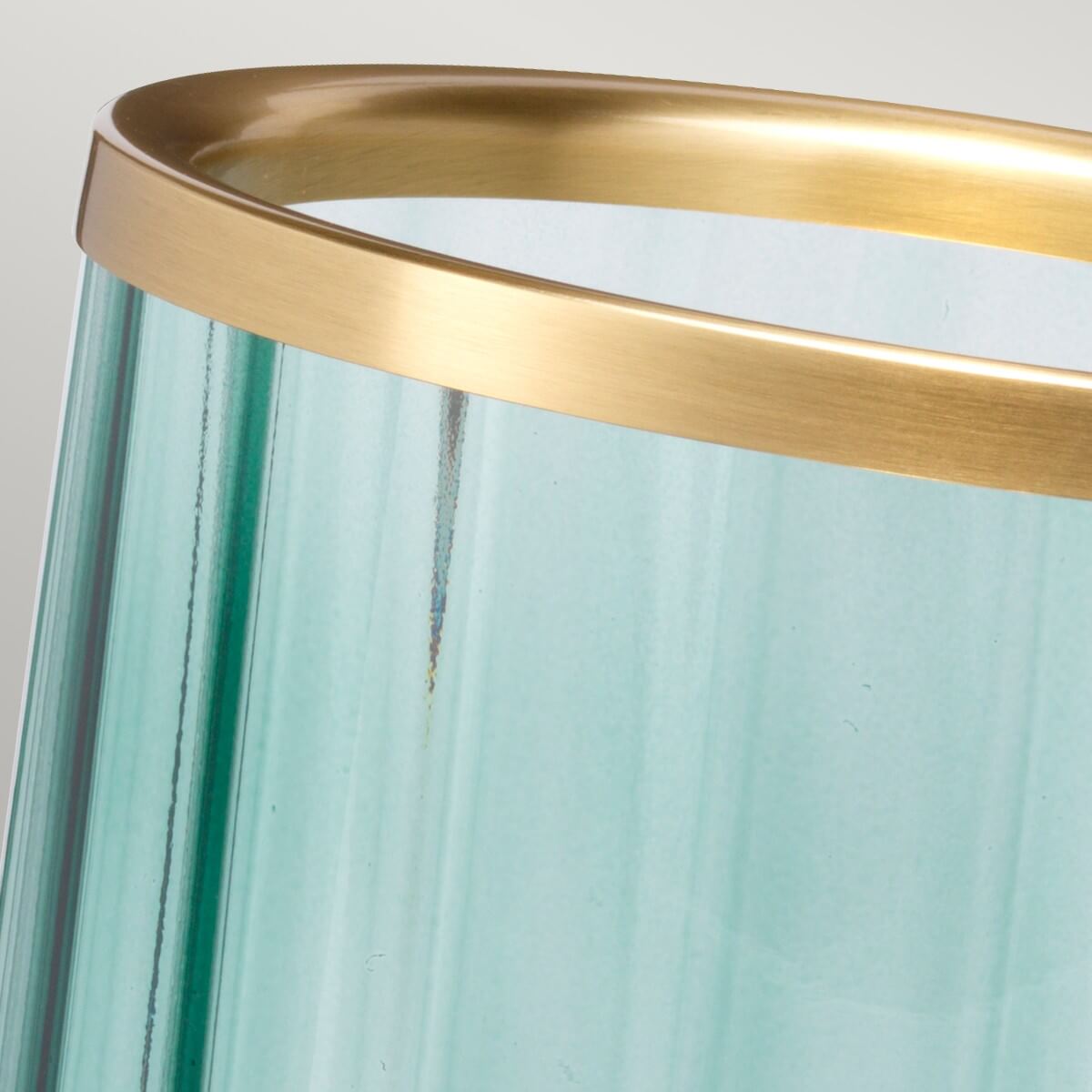 Gros plan sur le bord en laiton vieilli et la texture ondulée du verre vert.