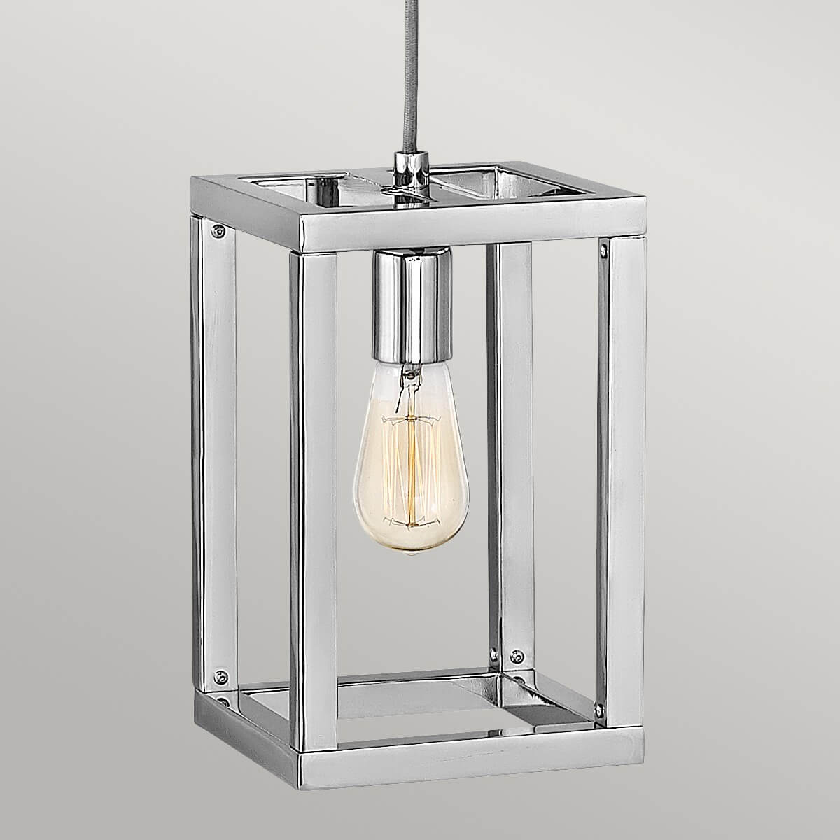 Gros plan sur la cage carrée en nickel poli et l'ampoule Edison allumée
