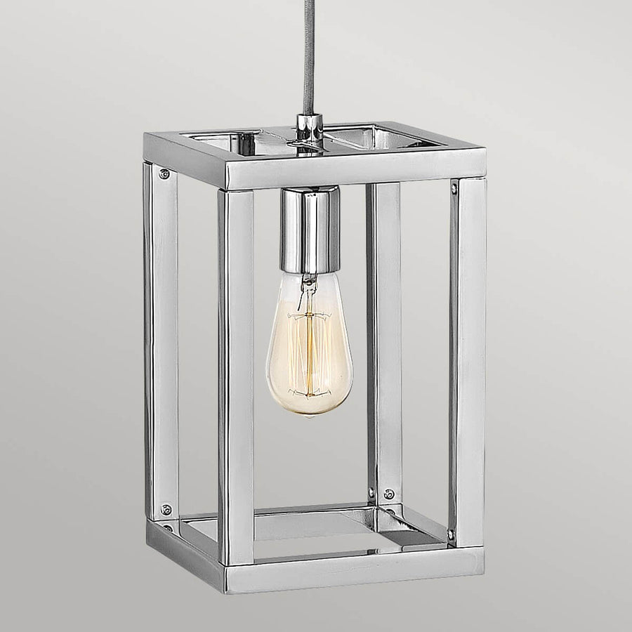 Gros plan sur la cage carrée en nickel poli et l'ampoule Edison allumée