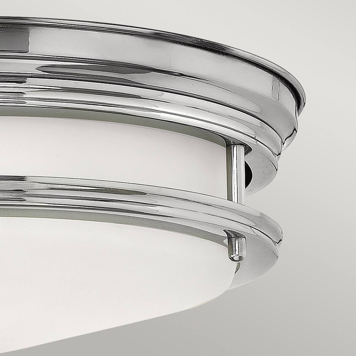 Gros plan sur la bague chromée et le verre blanc du plafonnier.