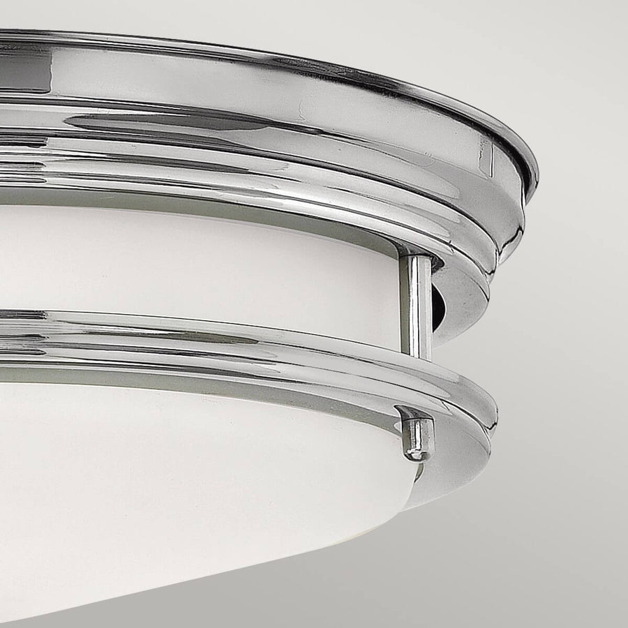 Gros plan sur la bague chromée et le verre blanc du plafonnier.