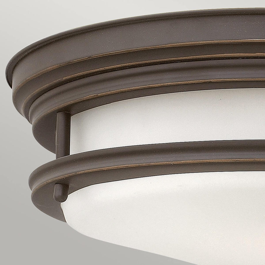 Détail du cerclage bronze patiné et du verre blanc dépoli du luminaire