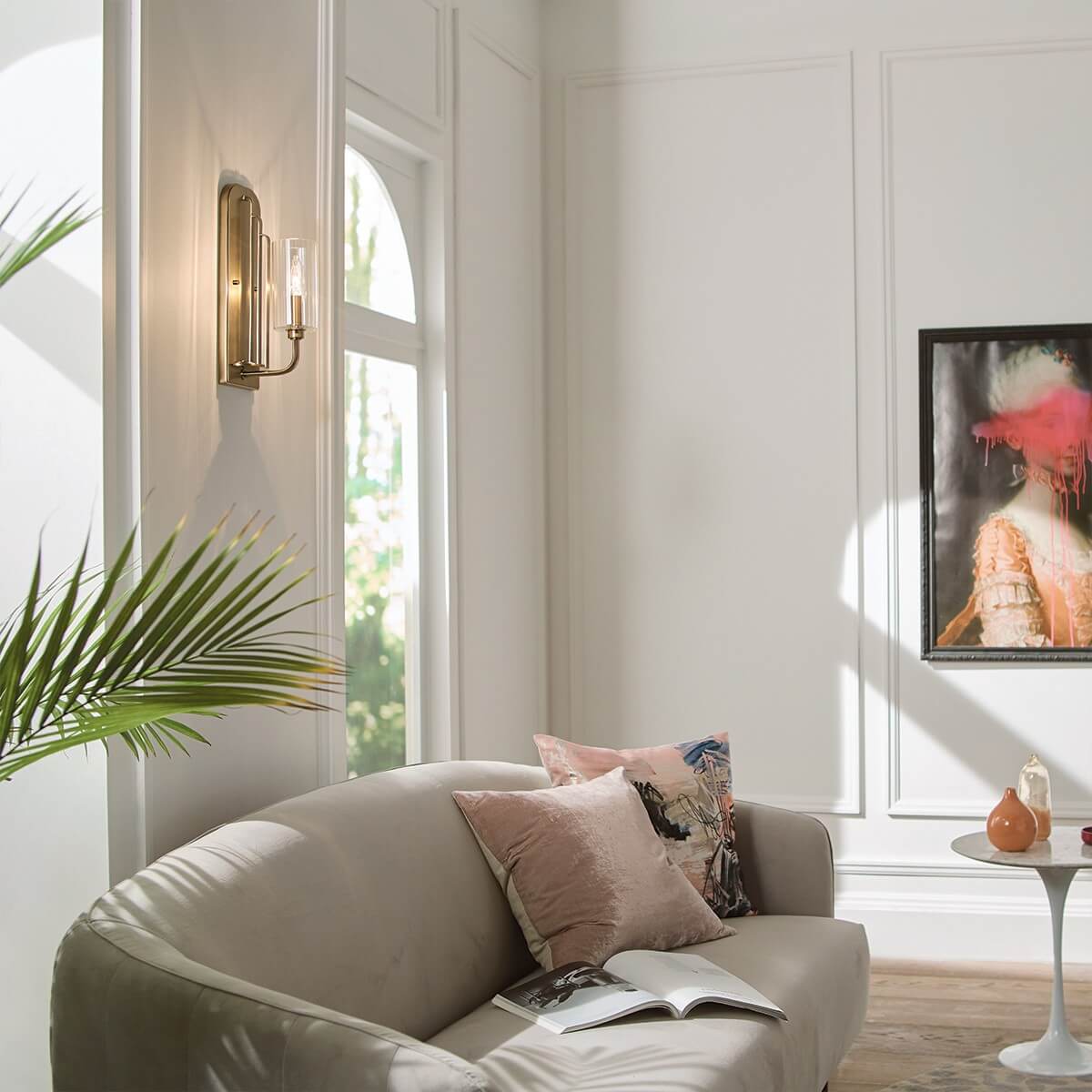 Mise en ambiance dans un salon avec canapé, tableau et plante verte.