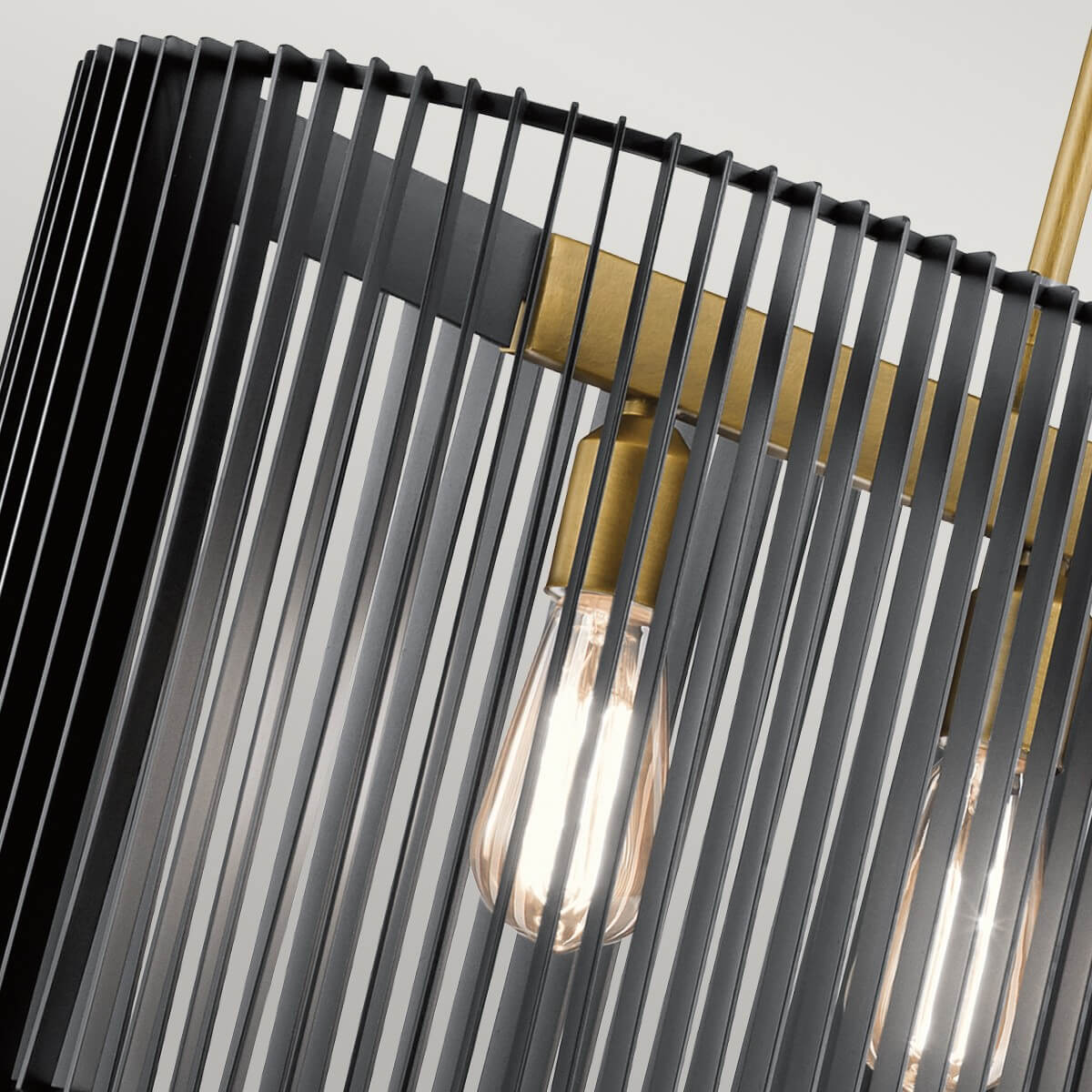 Gros plan sur une ampoule filament, la douille dorée et les lamelles noires du luminaire.