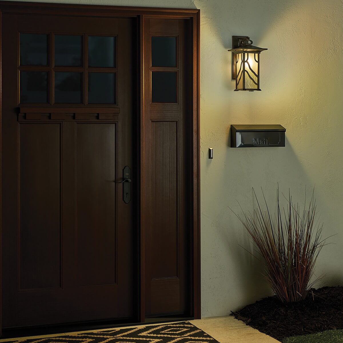 Mise en ambiance nocturne, applique allumée diffusant une lumière chaude près de la porte.