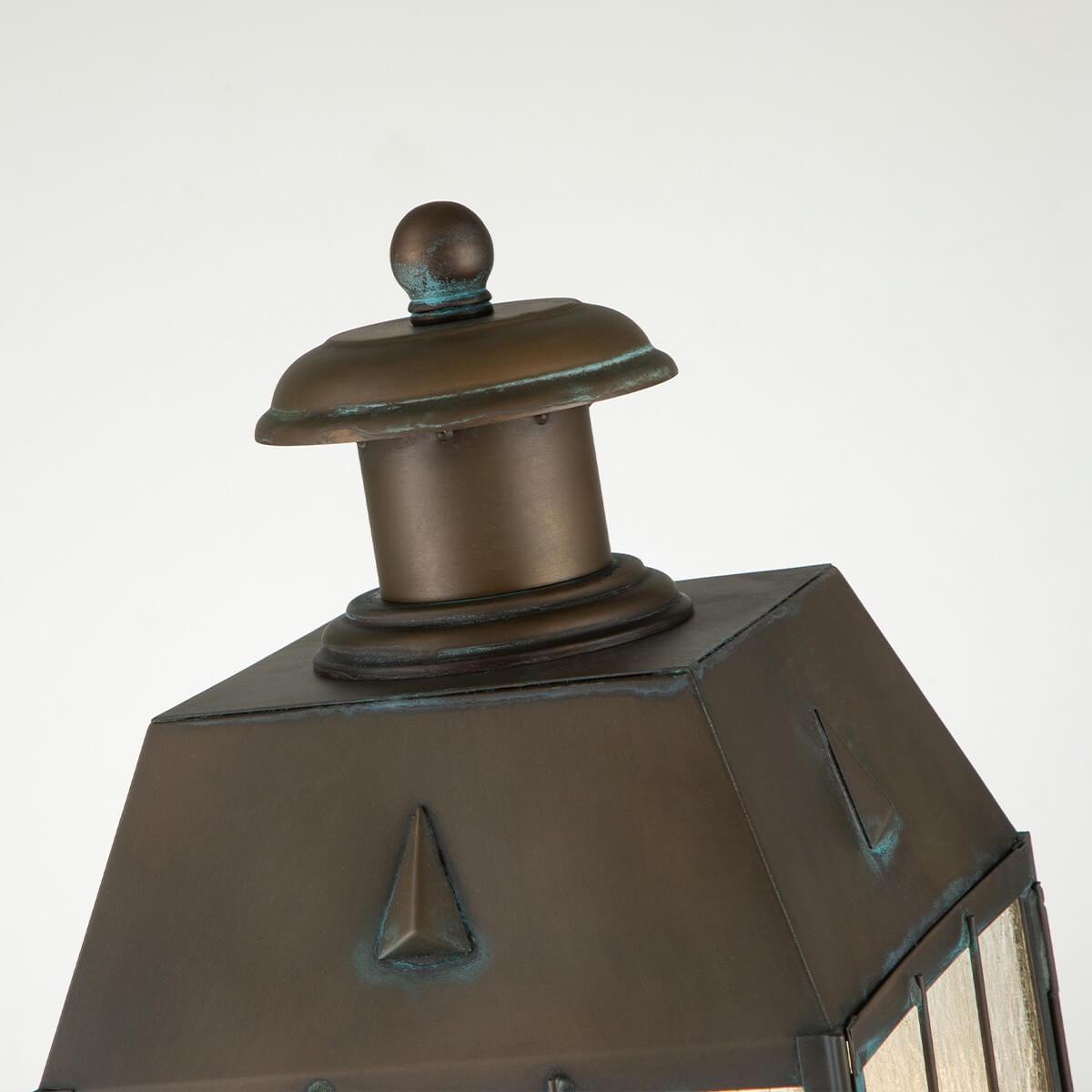 Détail du sommet avec finial boule, chapeau métallique et patine vert-de-gris.
