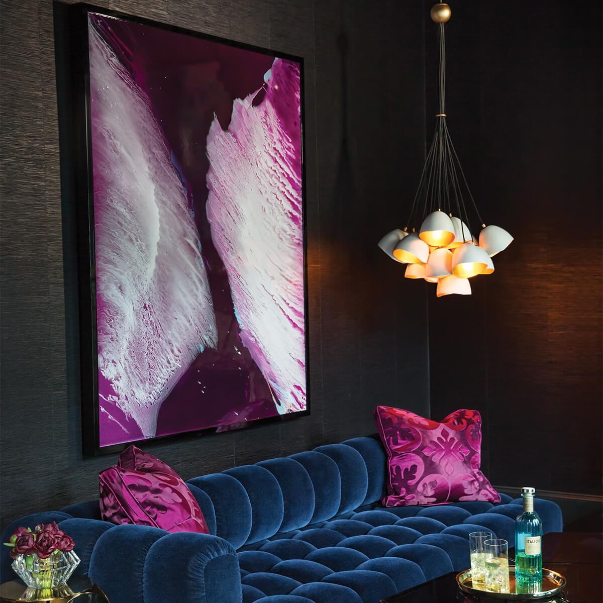 Mise en ambiance sur canapé bleu nuit avec tableau magenta et suspension allumée
