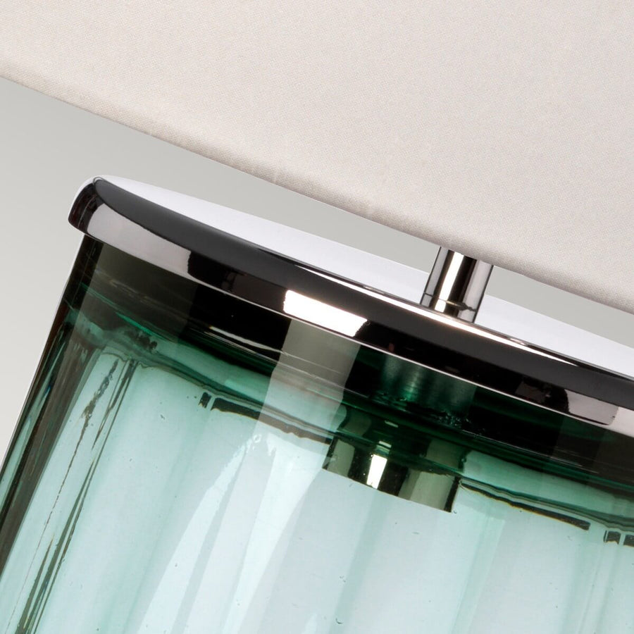 Détail du haut de la base en verre vert et de la bague en nickel poli.