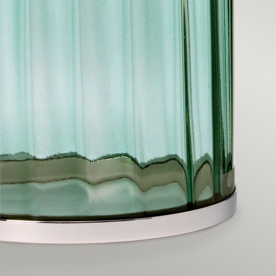 Détail du bas de la base en verre vert avec rebord ondulé et socle nickel poli.