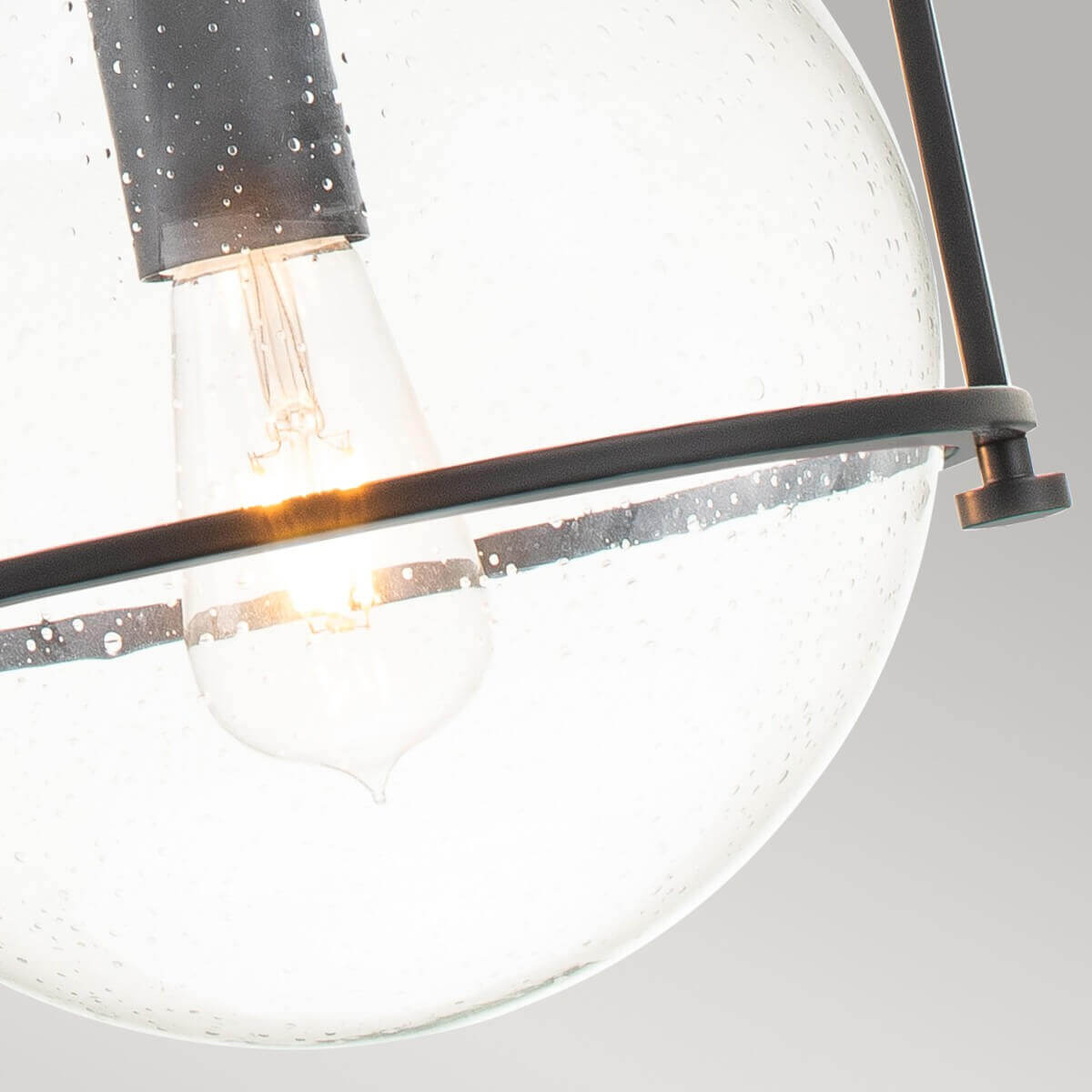 Vue rapprochée de l'ampoule allumée à travers le verre perlé et la bague noire