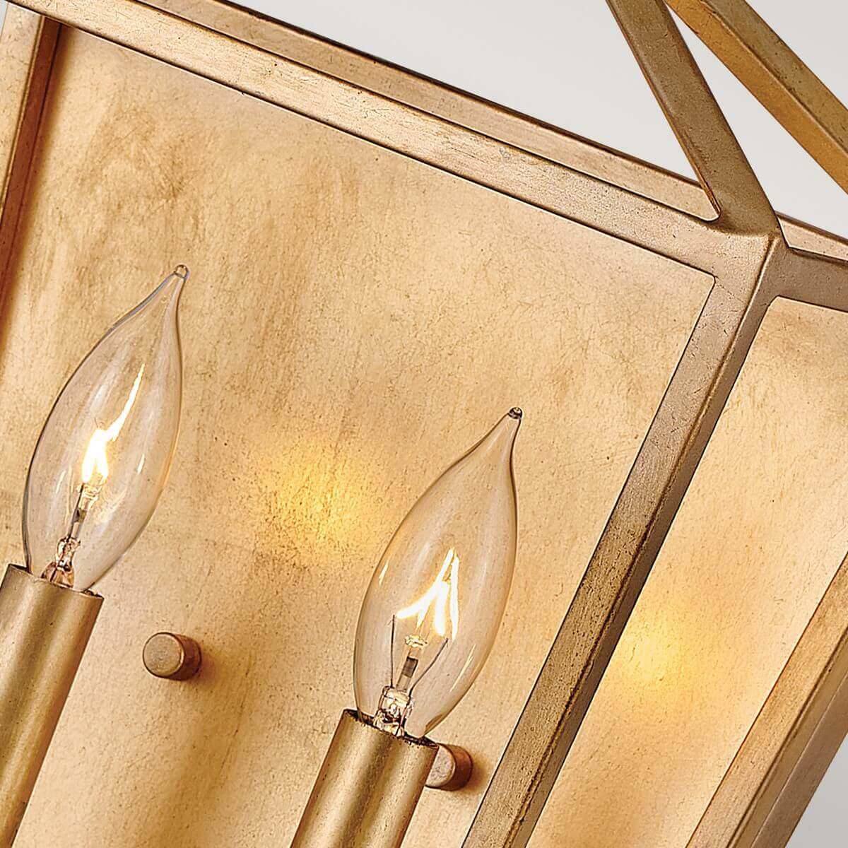 Vue rapprochée des deux ampoules bougies allumées et de la plaque arrière dorée.
