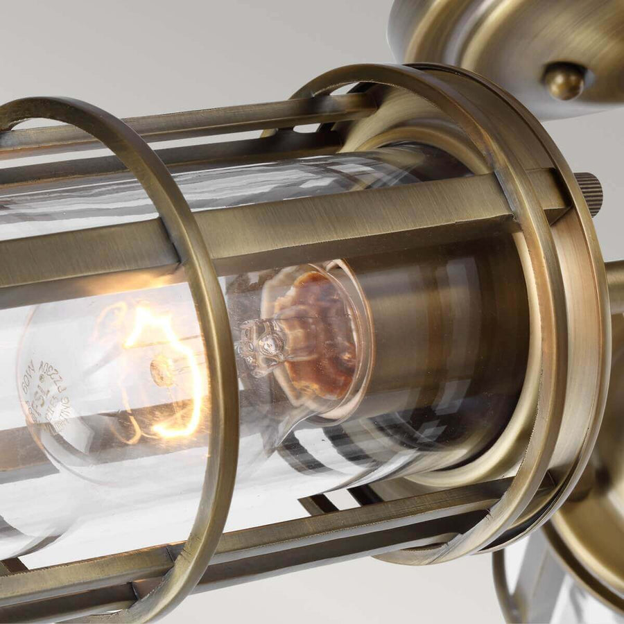Gros plan sur une cage cylindrique en laiton, ampoule allumée et verre transparent