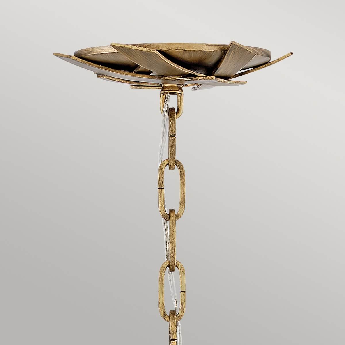 Détail du support plafond doré et chaîne de suspension avec câble transparent.