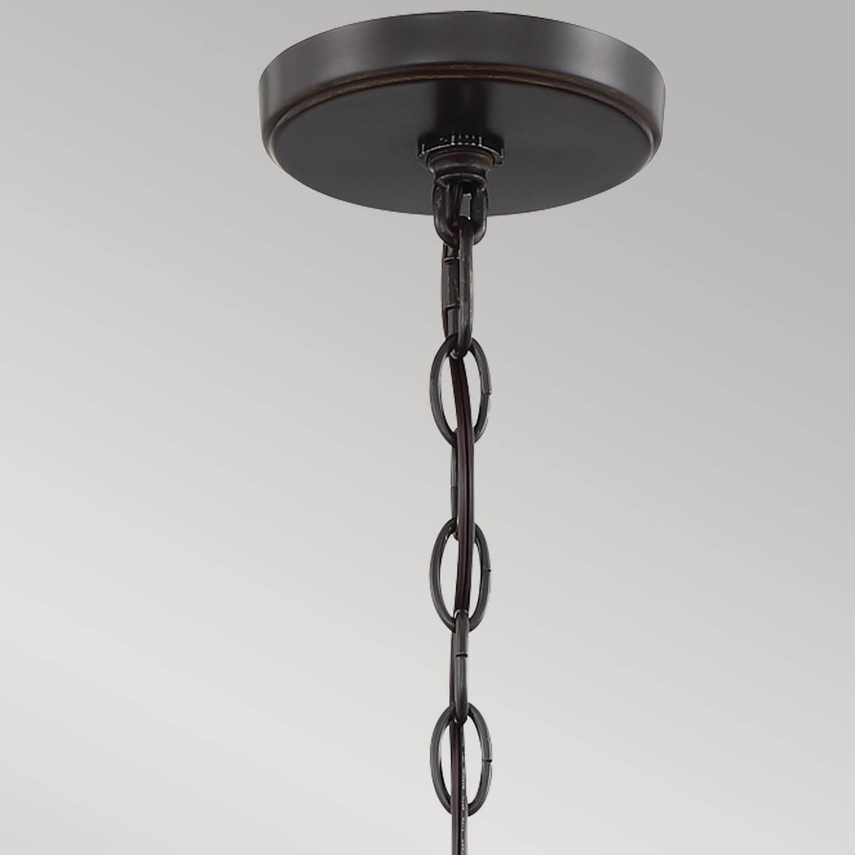 Gros plan sur la platine de fixation au plafond et la chaîne métallique de suspension.