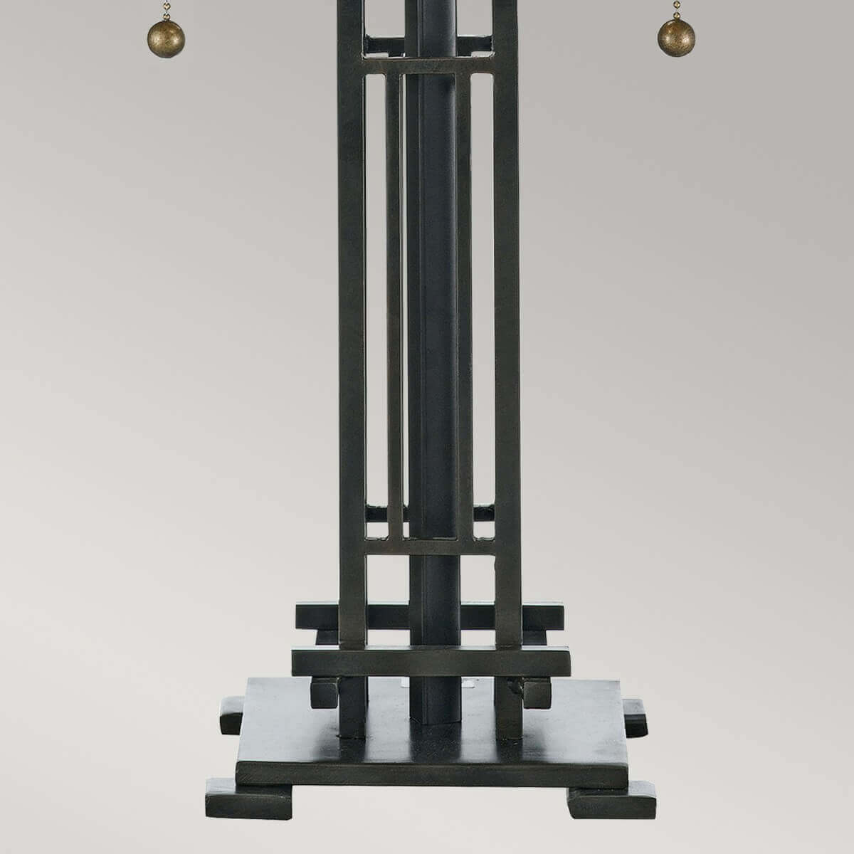 Détail du pied géométrique en métal bronze et des tirants latéraux de la lampe.