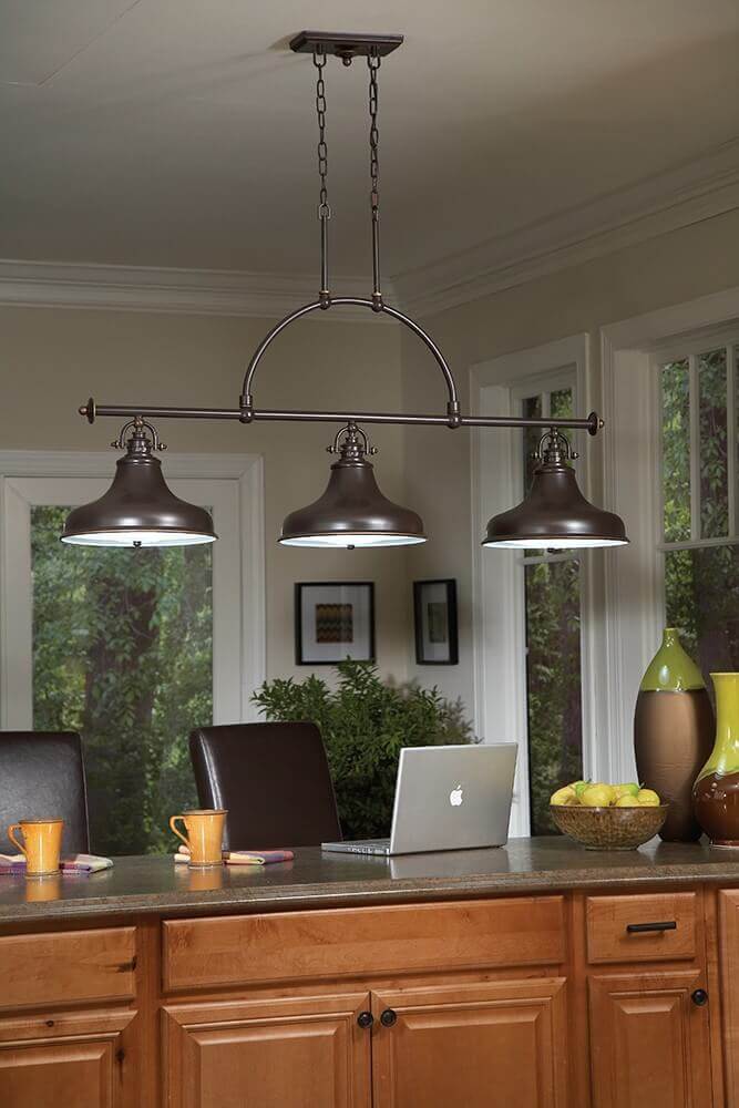 Luminaire installé au-dessus d'un îlot de cuisine en bois, avec ordinateur et chaises.