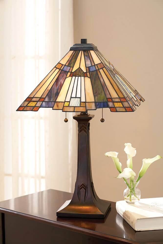 Lampe allumée sur table en bois près de livres et fleurs blanches