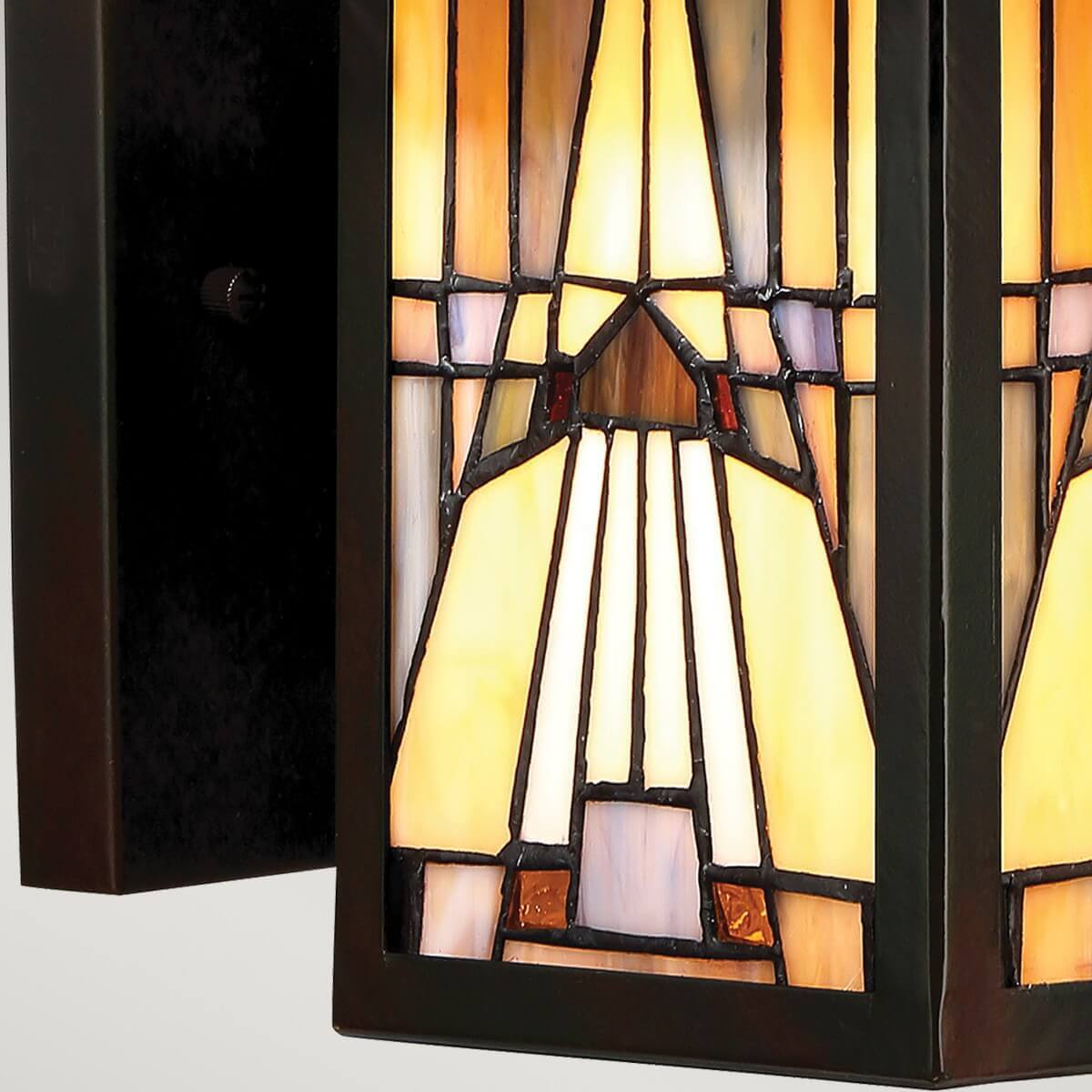 Gros plan du verre tiffany géométrique éclairé et de la platine murale.